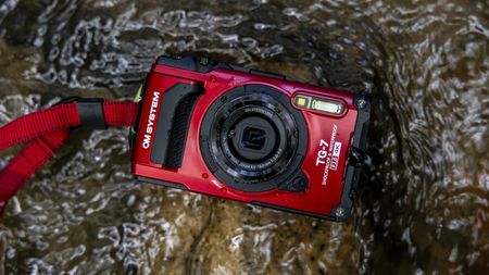 The OM System Tough TG-7 camera lying in a stream